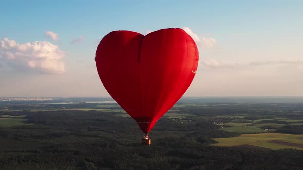 Red Heartshaped Balloon with People Over Green Fields and Forests