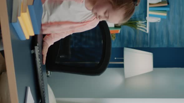 Vertical Video Little Girl Sitting at Desk Using Computer and Keyboard