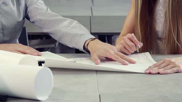 Two Person Working on Blueprint in Light Office