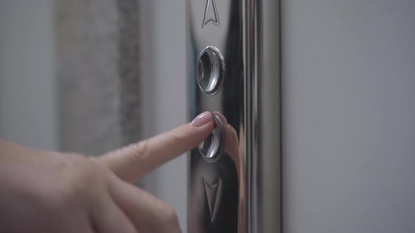 Close-up of Female Caucasian Finger Pressing Elevator Button. Unrecognizable Young Woman Pushing