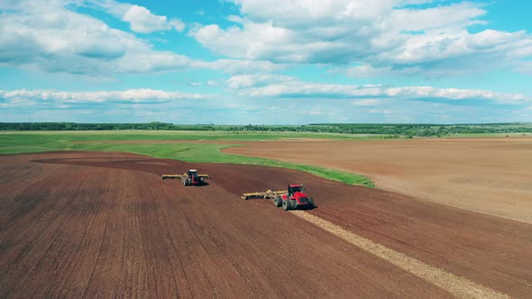 Two Tractors Work on a Big Farmland, Preparing for Sow