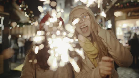 Pretty Young Girlfriends Laughing and Dancing with Sparklers in the Street