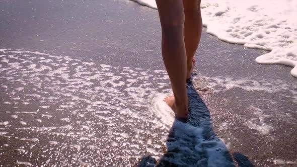 Woman's Legs Walking Along the Beach