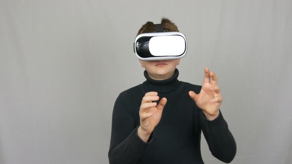 Teenager Boy Looks Into White Virtual Reality Glasses or VR and Has Fun on a White Background in the