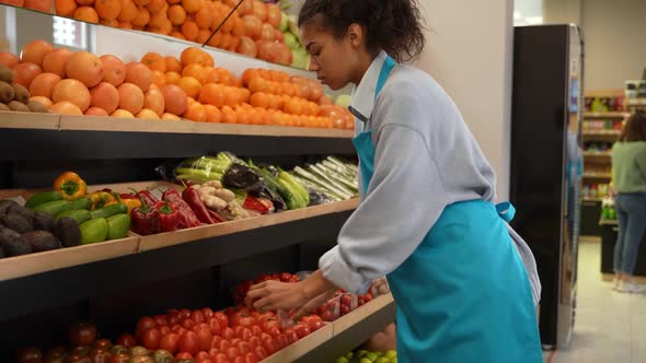 Female Worker Putting Tomatoes on Stand in Store