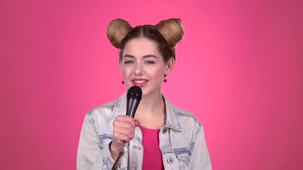 Teenager Sings Into the Microphone. Pink Background. Slow Motion