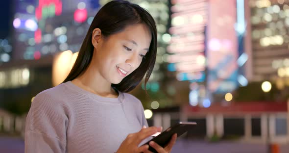 Asian Woman use of mobile phone in city at night