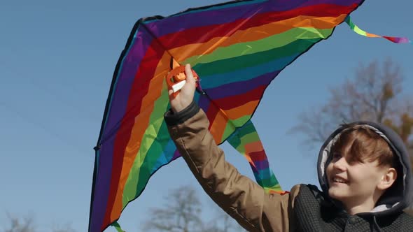 A Happy Boy is Playing with a Flying Rainbow Kite