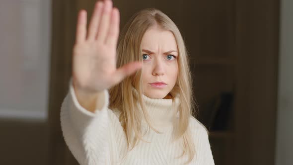 Portrait of Offended Blonde Caucasian Woman Makes Stop Gesture with Her Palm Forbidding Waving Head