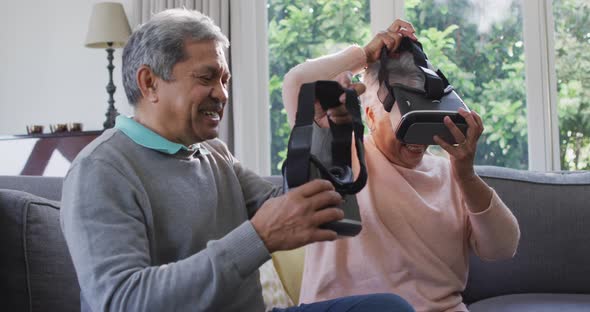 Happy mixed race senior couple wearing vr headset and having fun at home