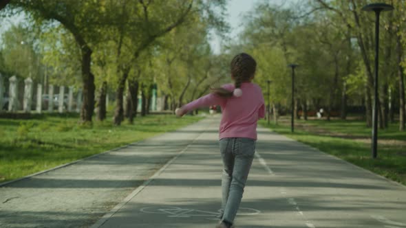 Playful Little Girl Runs Along Empty Road in Spring Park