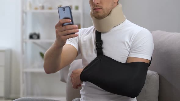 Man in Cervical Collar and Arm Sling Chatting Smartphone at Home, Rehabilitation