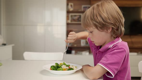 Boy Tries To Eat a Vegetables but Dosen't Like It and Rejects the Food. Healthy Food Concept