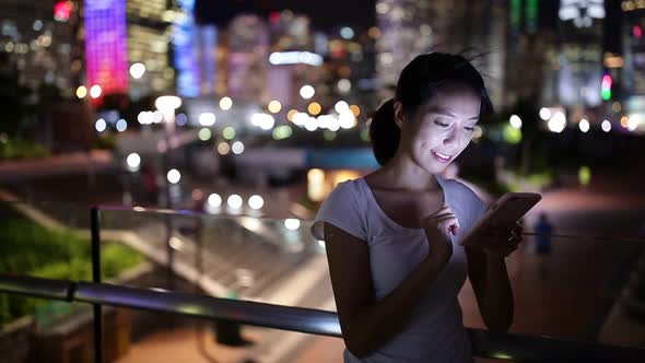 Woman sending text message on cellphone at night