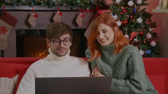 Happy couple celebrating Christmas with their friends using a video call.