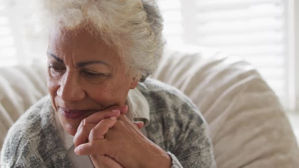 Close up of african american senior woman smiling while sitting on a bean bag at home