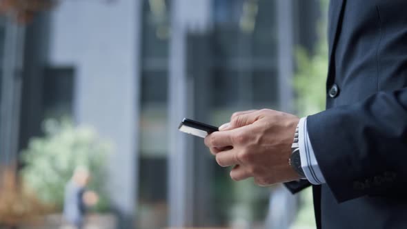 Male Hands Holding Smartphone Walking at Downtown Area in Morning Close Up