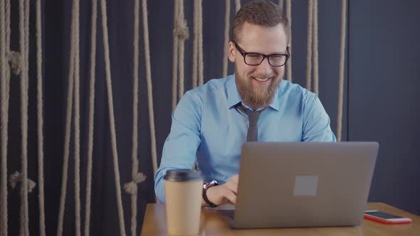 Happy Guy Businessman in a Cafe with Laptop.