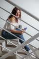 Woman sitting on stairs looking at messages on her smartphone - PhotoDune Item for Sale