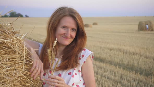 Portrait Of A Beautiful Young Smiling Girl Near The Round Bale