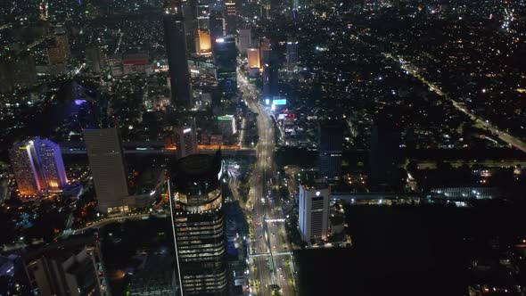 Wide Aerial View of Multi Lane Highway Traffic at Night in Modern Jakarta City Center with Tall