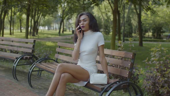 Pretty Black Woman Talking on Cellphone on Bench