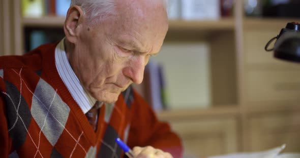 Senior Businessman Writing on Paper at Table in Office