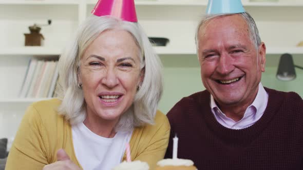 Portrait of happy senior caucasian couple celebrating a birthday making a video call