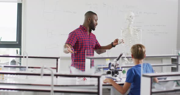 Video of happy african american teacher with class of diverse pupils during anatomy lesson