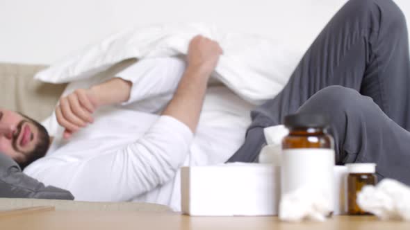 Sick Man Falling Down on Couch and Covering Himself with Blanket