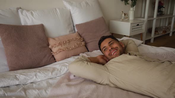 Happy but tired man falls on the bed after a hard day, wants to rest