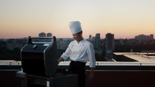 A professional Chef prepares a barbecue on the rooftop of a skyscraper. An expensive restaurant
