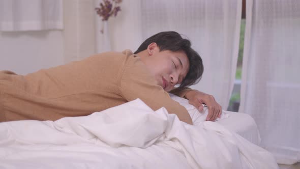 Asian man sleeping well in a comfy warm fresh bed on a soft pillow