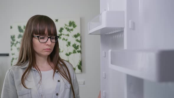 Refrigerator Without Food, Young Girl with Glasses Opens Refrigerator Door and Looks Sad Looking