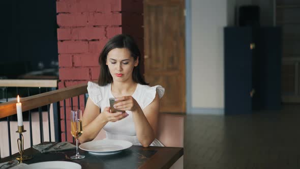 Attractive Young Woman in Beautiful Dress Is Waiting for Her Boyfriend in Restaurant Sitting at