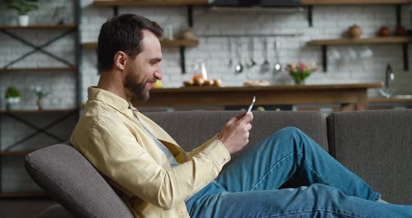 Young Man Playing on His Tablet Pc Exciting Mobile Application Racing Game While Resting on Couch in