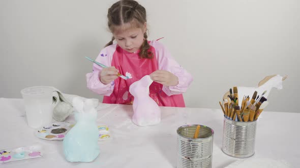 Little girl painting paper mache figurine at homeschooling art class.