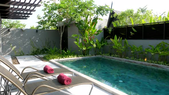 Sunbeds with Bath Towels on Terrace with Blue Swimming Pool and Garden in House