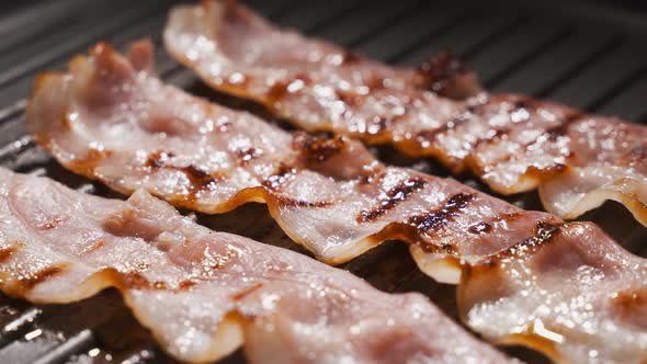 Pieces of Bacon Are Fried in a Pan. The Concept of Fatty and Junk Food, a Source of Trans Fats