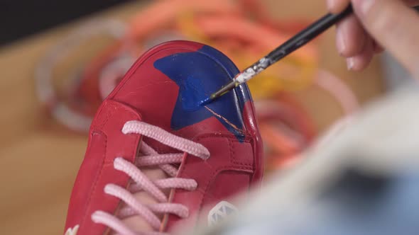 Closeup of Artist Fixing Sneakers Design By Painting It with Brush