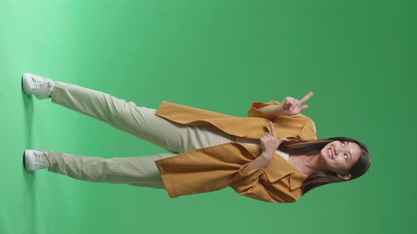 Full Body Of Asian Woman Smile And Pointing To The Side While Standing In The Green Screen Studio