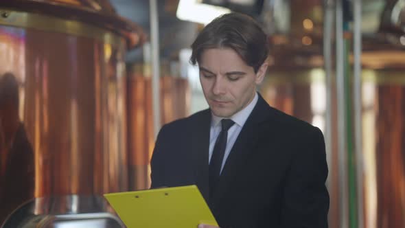 Male Caucasian Brewer Checking Beer Quality at Factory Leaving with Paperwork