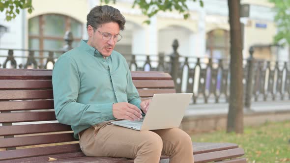 Man Feeling Angry while using Laptop on Bench