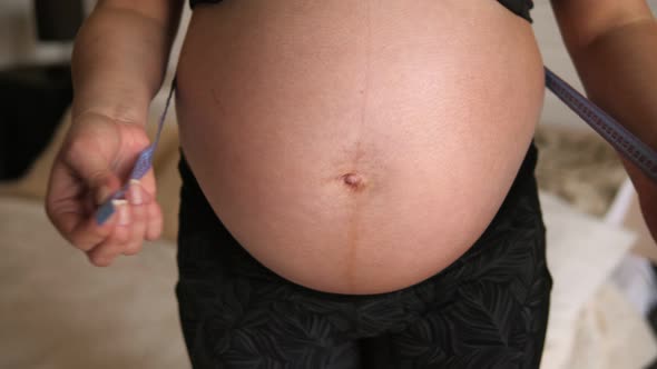 Closeup Belly of Pregnant Woman with Centimeter Tape Measure