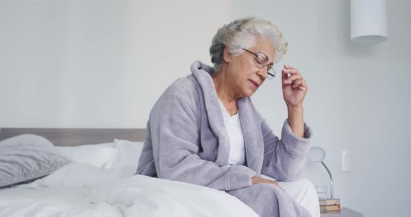 Stressed african american senior woman sitting on the bed at home