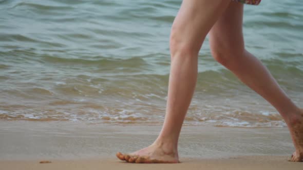 Muscular Legs Walk Along Beach Sand Against Waving Ocean