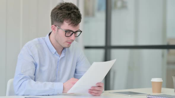 Young Man Reading Documents in Office