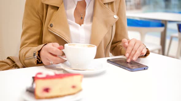  Video of Young Woman Browsing Social Media Website on Smartphone While Drinking Coffee in Cafe