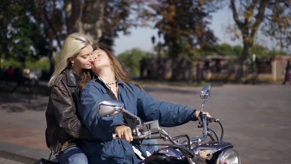 Lesbian Women in Love Sit on Motorcycle on the City Street