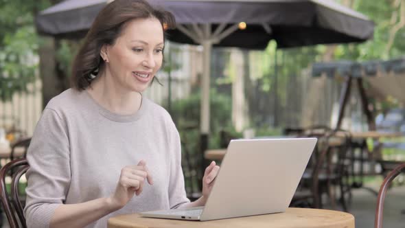 Video Chat By Old Woman Via Laptop Sitting in Outdoor Cafe